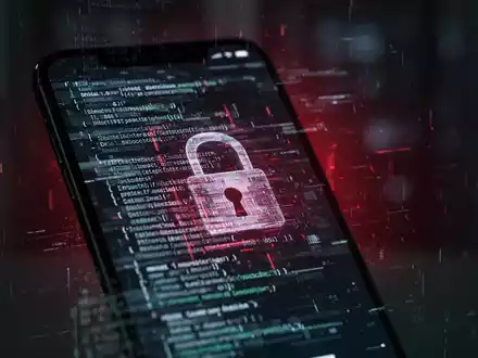Nahaufnahme eines Smartphone-Bildschirms, der glitchigen Code oder ein digitales Schloss mit einem schwachen roten Leuchten anzeigt. - Foto: über boerse-global.de