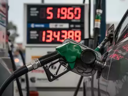 Eine Zapfsäule mit einer Tankpistole, die Benzin in ein Auto füllt, im Hintergrund eine digitale Preisanzeige mit Zahlen. - Foto: über boerse-global.de