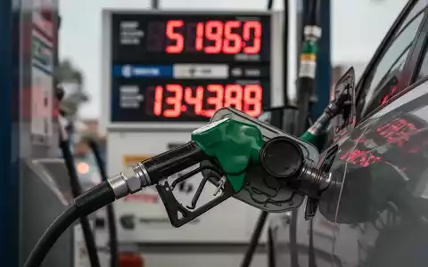 Eine Zapfsäule mit einer Tankpistole, die Benzin in ein Auto füllt, im Hintergrund eine digitale Preisanzeige mit Zahlen. - Foto: über boerse-global.de