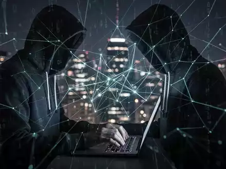 A person in a hoodie types on a laptop, surrounded by glowing digital lines, symbolizing cybercrime and phishing scams. - Foto: über boerse-global.de