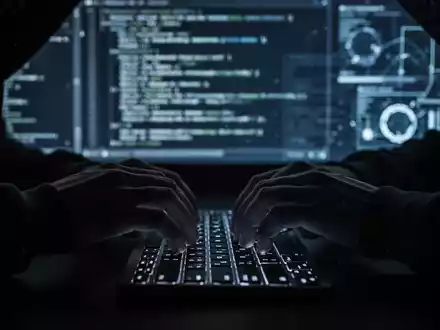 Hände tippen auf einer leuchtenden Tastatur, im Hintergrund verschwommene digitale Datenlinien, die Cyberkriminalität symbolisieren. - Foto: über boerse-global.de