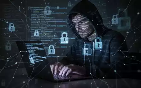 A shadowy figure in a hoodie types on a laptop, with lines of code and digital lock icons overlaid, symbolizing a cyberattack. - Foto: über boerse-global.de