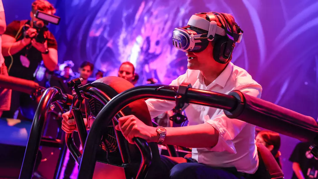 Ein wilder Ritt bei der Gamescom 2024: Hendrik Wüst auf einem «Drachen», genauer gesagt mit virtueller Brille auf einem schwankenden Gestell. - Bild: Oliver Berg/dpa