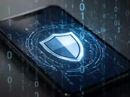 Ein Smartphone-Bildschirm zeigt ein Schildsymbol, mit subtilen binären Codes im Hintergrund, die Cybersicherheit und Datenschutz symbolisieren. - Foto: über boerse-global.de
