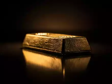 Ein glänzender Goldbarren, teilweise im Schatten, auf einer dunklen, reflektierenden Oberfläche. - Foto: über boerse-global.de