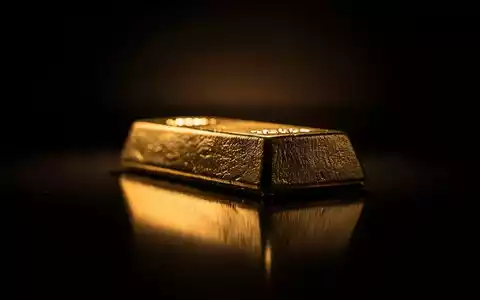 Ein glänzender Goldbarren, teilweise im Schatten, auf einer dunklen, reflektierenden Oberfläche. - Foto: über boerse-global.de