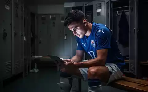Ein Fußballspieler sitzt nachdenklich in einer Umkleidekabine, symbolisiert mentale Vorbereitung und psychologische Unterstützung im Sport. - Foto: über boerse-global.de