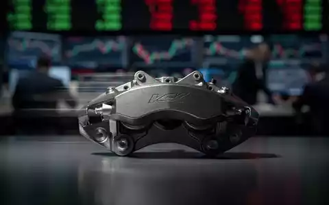 Ein einzelner, glänzender Bremsattel vor einem unscharfen Hintergrund eines Börsenparketts, der eine Verlangsamung andeutet. - Foto: über boerse-global.de