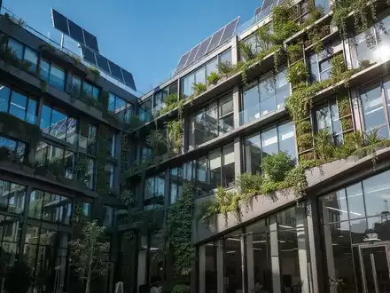 Eine moderne, nachhaltige Bürogebäude-Fassade mit grünen Elementen, die Umweltbewusstsein und Energieeffizienz symbolisiert. - Foto: über boerse-global.de