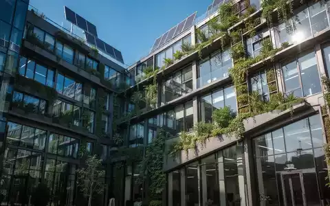 Eine moderne, nachhaltige Bürogebäude-Fassade mit grünen Elementen, die Umweltbewusstsein und Energieeffizienz symbolisiert. - Foto: über boerse-global.de
