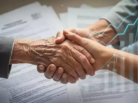 Eine ältere Hand hält eine jüngere Hand, mit verschwommenen Dokumenten und Finanzgrafiken im Hintergrund, symbolisiert Pflege und Reform. - Foto: über boerse-global.de