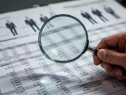 Eine Hand hält eine Lupe über eine Betriebskostenabrechnung, die Details und Zahlen zeigt, symbolisiert Prüfung und Transparenz. - Foto: über boerse-global.de
