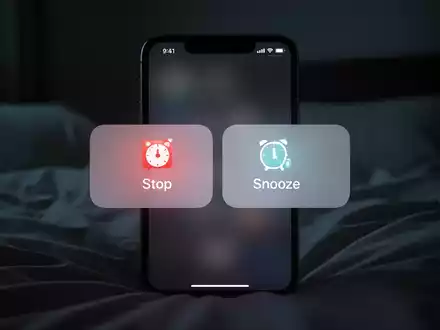 A close-up of a smartphone screen displaying an alarm with equally sized 'Stop' and 'Snooze' buttons. - Foto: über boerse-global.de