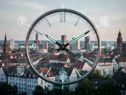 Ein stilisiertes Zifferblatt mit schnell bewegten Zeigern, überlagert von digitalen Symbolen für Unternehmensgründung, vor der Stadt Bielefeld. - Foto: über boerse-global.de