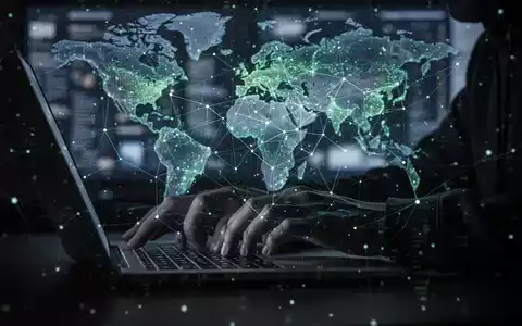 Shadowy figure's hands typing on a laptop with a glowing digital network overlay, symbolizing cybercrime and data theft. - Foto: über boerse-global.de
