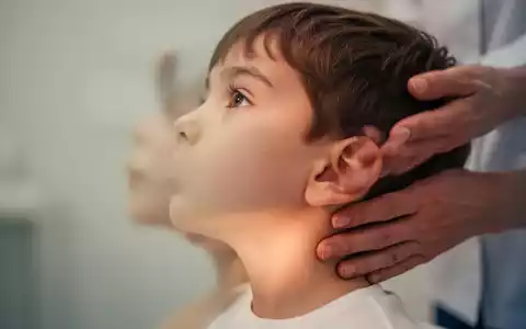 Ein Kind im Profil, dessen Kiefer- und Nackenbereich im Fokus liegt, mit einer unscharfen Hand eines Erwachsenen in der Nähe. - Foto: über boerse-global.de