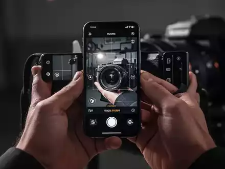 Close-up of hands holding an iPhone displaying a professional camera app with advanced editing tools. - Foto: über boerse-global.de