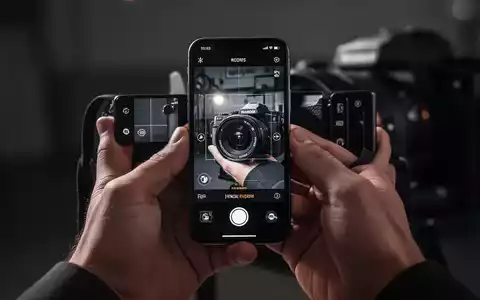 Close-up of hands holding an iPhone displaying a professional camera app with advanced editing tools. - Foto: über boerse-global.de