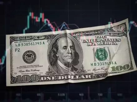 Eine einzelne US-Dollarnote mit einem subtilen, abwärts gerichteten Graph im Hintergrund, der eine verfehlte Erwartung symbolisiert. - Foto: über boerse-global.de