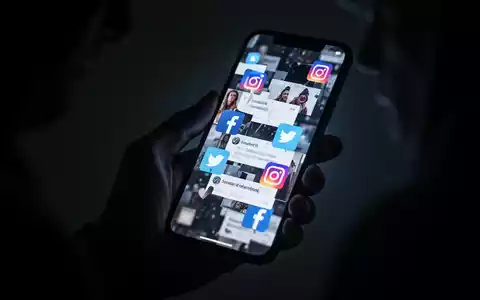 A shadowy hand holds a smartphone displaying distorted social media icons, symbolizing tech-enabled abuse and digital threats. - Foto: über boerse-global.de