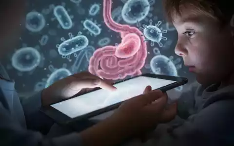 Nahaufnahme einer Kinderhand, die ein leuchtendes Tablet hält, mit unscharfen, abstrakten Bakterienformen im Hintergrund. - Foto: über boerse-global.de