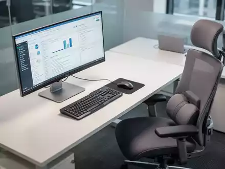 Ein ergonomisch eingerichteter Schreibtisch mit Monitor, Tastatur, Maus und einem modernen Bürostuhl, von oben betrachtet. - Foto: über boerse-global.de
