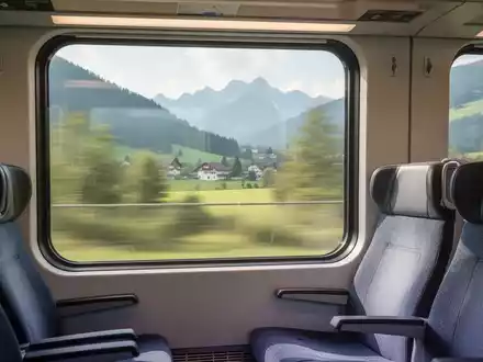 Innenansicht eines modernen Zuges mit Blick aus dem Fenster auf eine verschwommene bayerische Landschaft, leere Sitze im Vordergrund. - Foto: über boerse-global.de