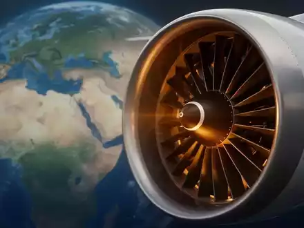 Eine Nahaufnahme eines modernen Flugzeugturbinenmotors, teilweise golden beleuchtet, vor einem unscharfen Hintergrund einer Weltkarte. - Foto: über boerse-global.de