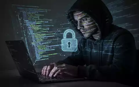 Eine Person im Kapuzenpulli tippt auf einem Laptop, mit leuchtenden Codezeilen, die ihr Gesicht und den Bildschirm beleuchten, symbolisiert Cyberbedrohungen. - Foto: über boerse-global.de