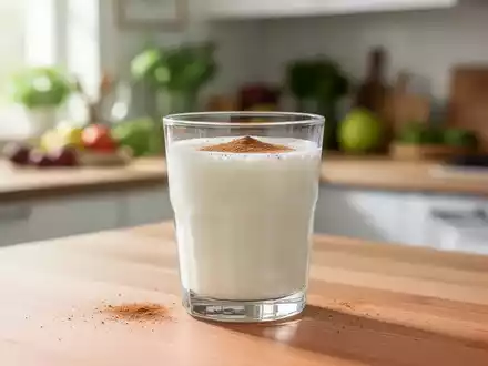 Ein Glas Buttermilch mit Zimt auf einer Holzoberfläche in einer hellen Küche, das gesunde Ernährung symbolisiert. - Foto: über boerse-global.de