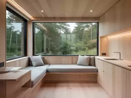 Innenansicht eines modernen Tiny Houses mit minimalistischem Design, Holzoberflächen und einem großen Fenster, das Natur zeigt. - Foto: über boerse-global.de
