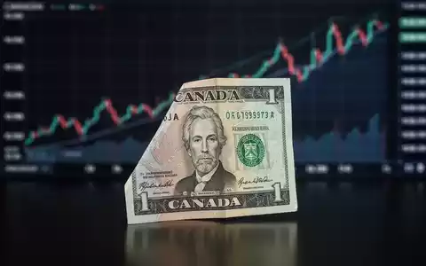 Eine aufrecht stehende kanadische Dollarnote vor einem unscharfen, aufsteigenden Finanzchart, symbolisiert Wachstum und Investition. - Foto: über boerse-global.de