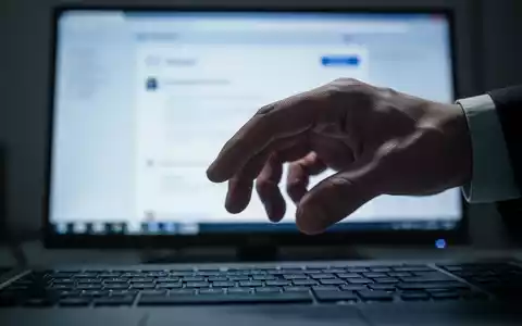 Hand hovering over a computer keyboard, with a blurred screen displaying an email interface in the background. - Foto: über boerse-global.de