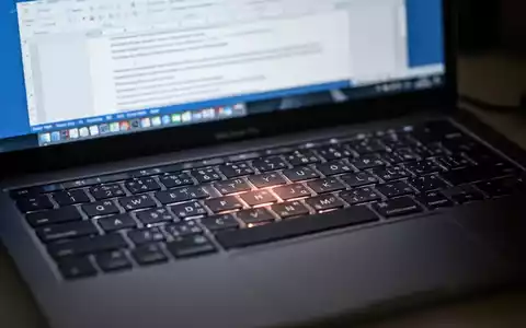 Close-up of a MacBook Pro keyboard with a blurred Microsoft Word document open on the screen in the background. - Foto: über boerse-global.de