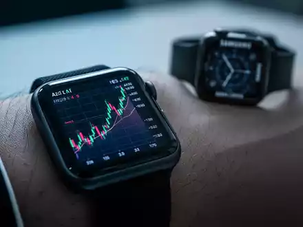 Eine Apple Watch mit einem aufsteigenden Diagramm am Handgelenk, im Hintergrund eine unscharfe, deprimierte Samsung Smartwatch. - Foto: über boerse-global.de