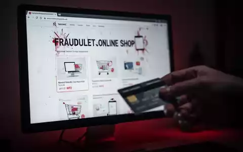Ein unscharfer Computerbildschirm zeigt einen betrügerischen Online-Shop, eine Hand greift nach einer Kreditkarte. Symbolisiert Online-Betrug. - Foto: über boerse-global.de