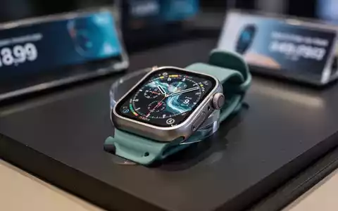 Close-up of an Apple Watch Ultra 3 with a titanium casing and an ocean band, resting on a dark, reflective surface. - Foto: über boerse-global.de