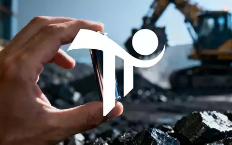 Eine Hand hält eine Lithium-Ionen-Batteriezelle vor einem unscharfen Hintergrund mit Bergbauausrüstung. - Foto: über boerse-global.de