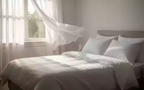 Ein von Sonnenlicht durchflutetes Schlafzimmer mit einem frisch aussehenden Bett, das mit weißen Bettdecken und Kissen bezogen ist. - Foto: über boerse-global.de