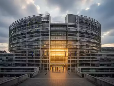 Das Europäische Parlament in Brüssel, mit dramatischen Wolken und einem goldenen Licht, das Stabilität und Reichtum symbolisiert. - Foto: über boerse-global.de
