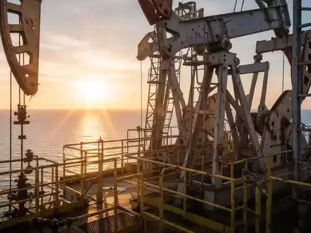 Eine Nahaufnahme einer Ölbohrplattform bei Sonnenaufgang, mit glitzernden Metallstrukturen und ruhigem Meer, das Stärke symbolisiert. - Foto: über boerse-global.de
