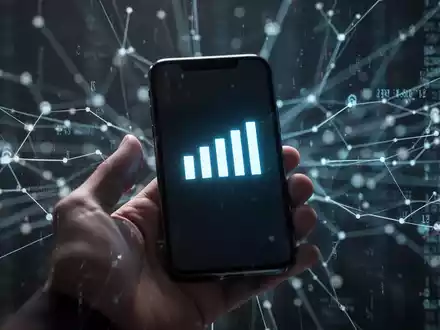A hand holds a modern smartphone with network signal bars on screen, against a background of abstract digital network lines. - Foto: über boerse-global.de