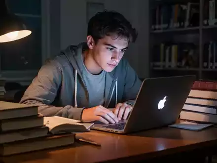 Student lernt nachts an einem Schreibtisch mit Büchern und Laptop, sanftes Bildschirmlicht. - Foto: über boerse-global.de