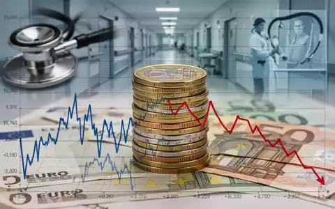 Ein Stapel Euro-Münzen und -Banknoten vor einem Diagramm mit Abwärtstrend und angedeuteten medizinischen Elementen im Hintergrund. - Foto: über boerse-global.de