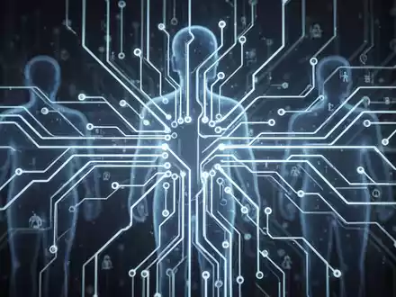 Eine stilisierte Darstellung eines leuchtenden neuronalen Netzwerks oder einer Platine mit verschwommenen menschlichen Silhouetten im Hintergrund. - Foto: über boerse-global.de