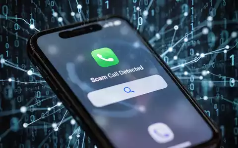 Close-up of an iPhone screen showing a 'Scam Call Detected' notification, with a blurred background of binary code. - Foto: über boerse-global.de