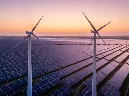 Ein riesiger Solarpark bei Sonnenaufgang mit Reihen von Photovoltaikmodulen und einer einzelnen Windkraftanlage. - Foto: über boerse-global.de