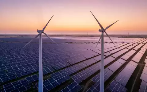 Ein riesiger Solarpark bei Sonnenaufgang mit Reihen von Photovoltaikmodulen und einer einzelnen Windkraftanlage. - Foto: über boerse-global.de
