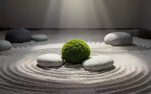 Ein ruhiger, minimalistischer Zen-Garten mit geharktem Sand, glatten grauen Steinen und einem einzelnen Moosball. - Foto: über boerse-global.de