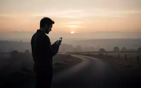 Eine Person steht auf einem einsamen Weg und schaut in die Ferne, während sie ein Smartphone hält. - Foto: über boerse-global.de